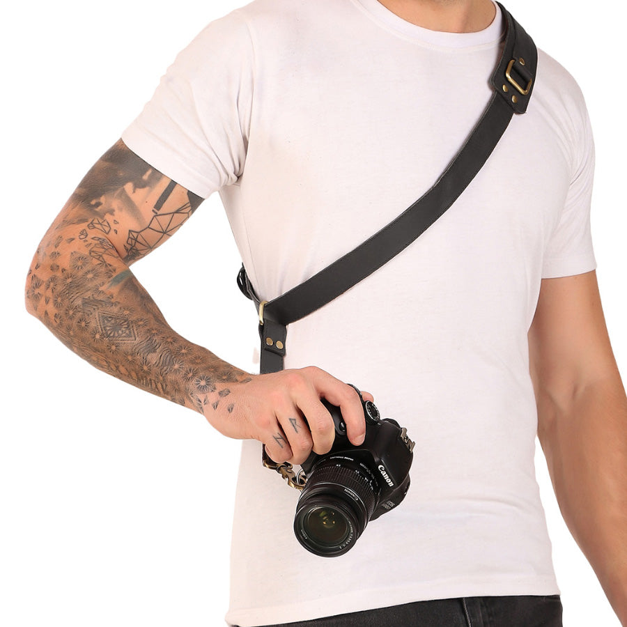 Person holding a camera with a black strap on a white background