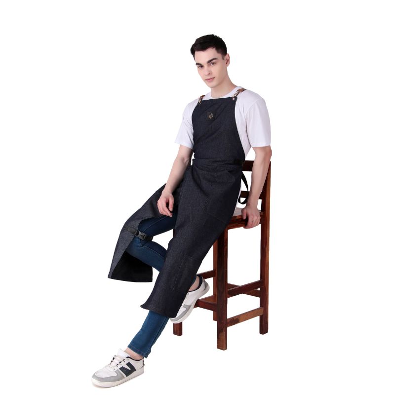 Person wearing a black apron sitting on a wooden chair against a white background