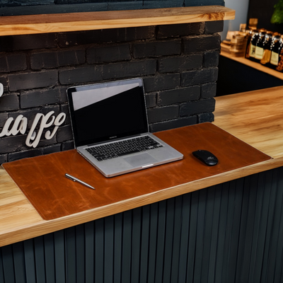 Laptop on a wooden desk with a brick wall and shelves in the background
