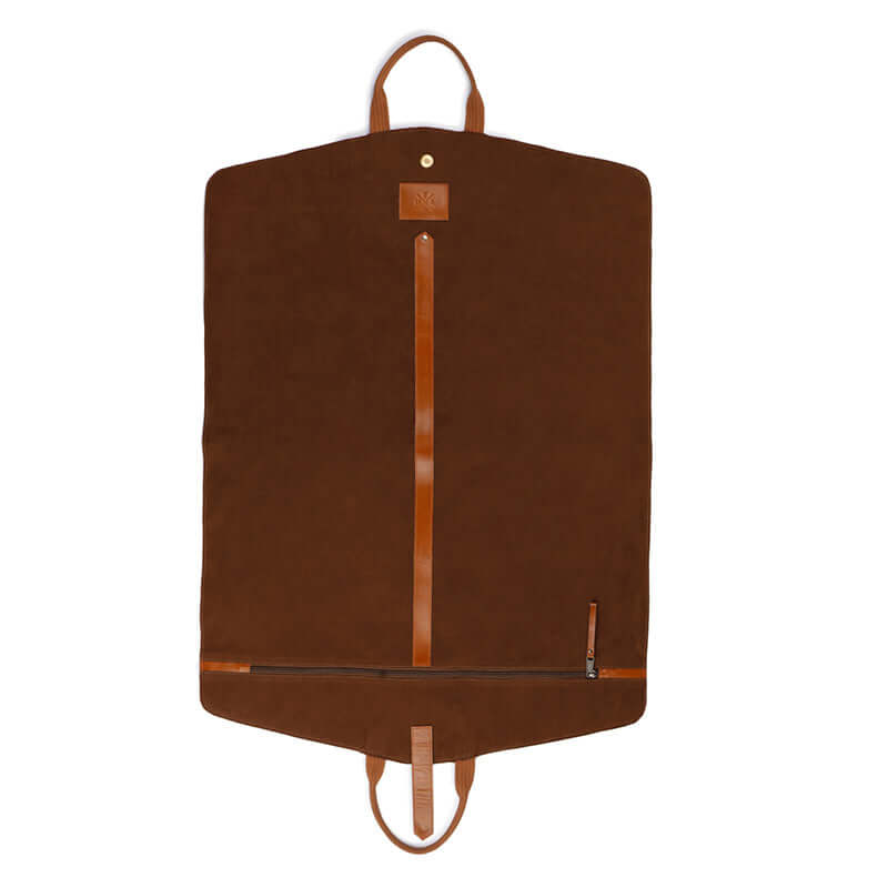 A black leather suit cover bag with brown trim and handles, laid out on a bed, displaying the interior with a suit hanging inside and compartments for storage.