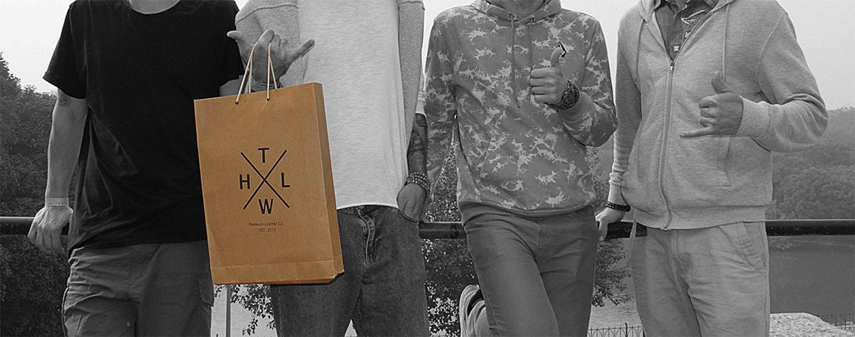 A diverse group of people standing together, smiling and engaging in conversation outdoors. tlwh