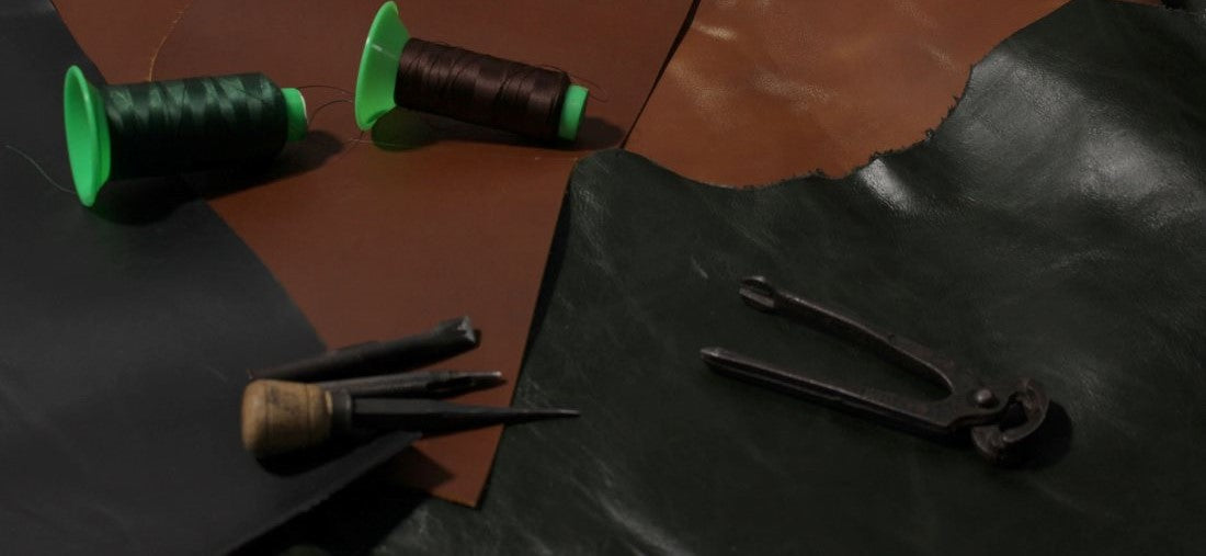 A leather workbench displaying various tools and colorful spools of thread arranged neatly on its surface.