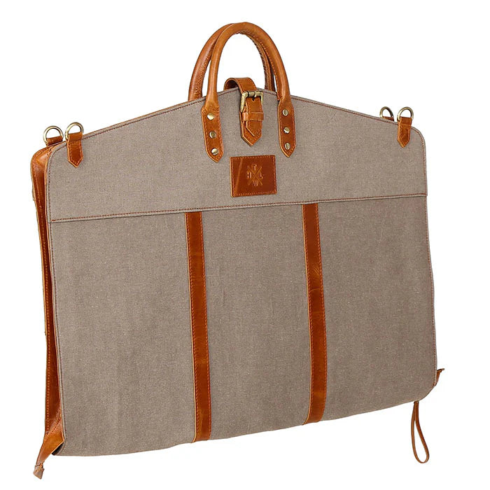 Beige garment bag with brown leather straps and handle on a white background