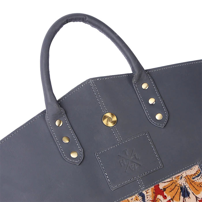 Gray tote bag with gold accents and a brand logo on a white background