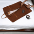 A brown leather garment bag with a soft velvet lining is laid out on a bed, with a person&