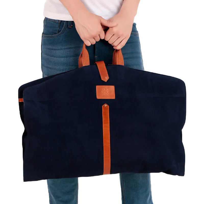 Person holding a navy blue bag with brown straps on a white background