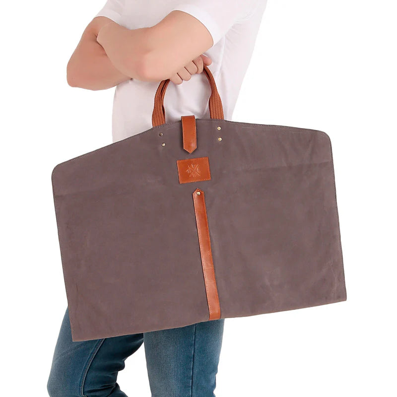 Person holding a large gray bag with brown handles and accents on a white background