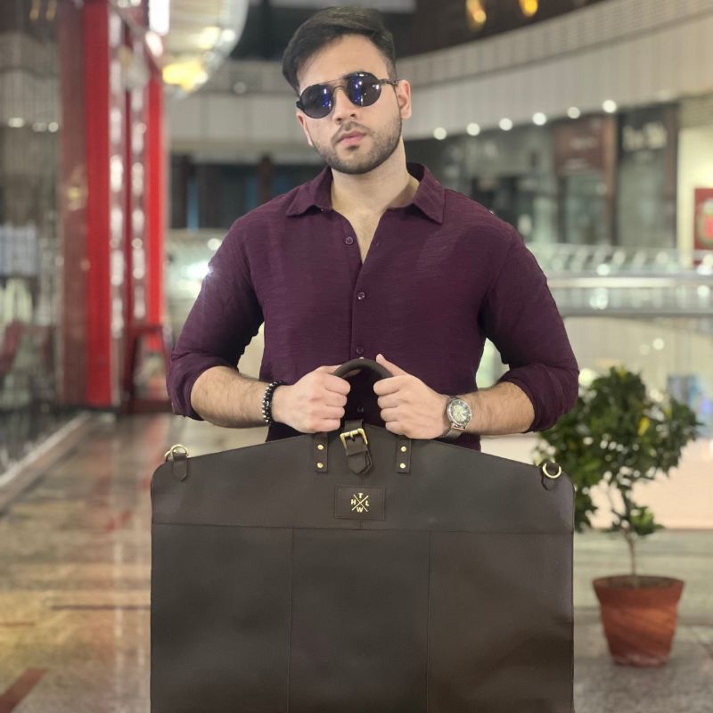 Man holding a black garment bag in an indoor setting