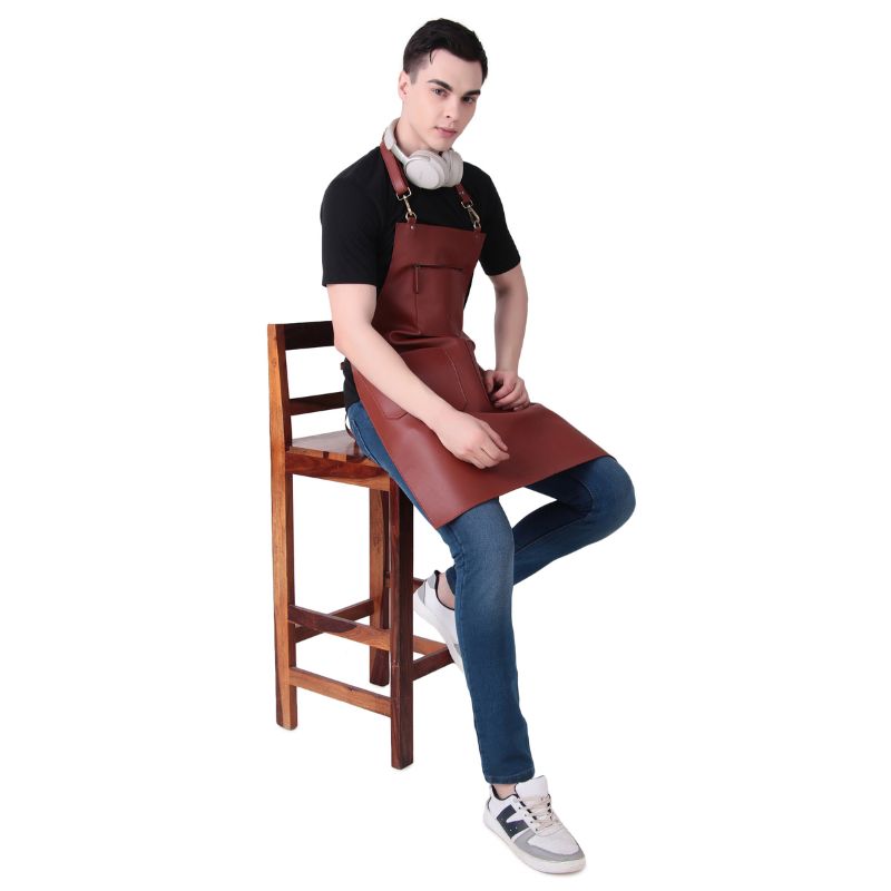 Person wearing a Rich Tan apron sitting on a wooden stool against a white background