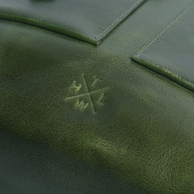 Close-up of a green leather bag with an embossed logo.