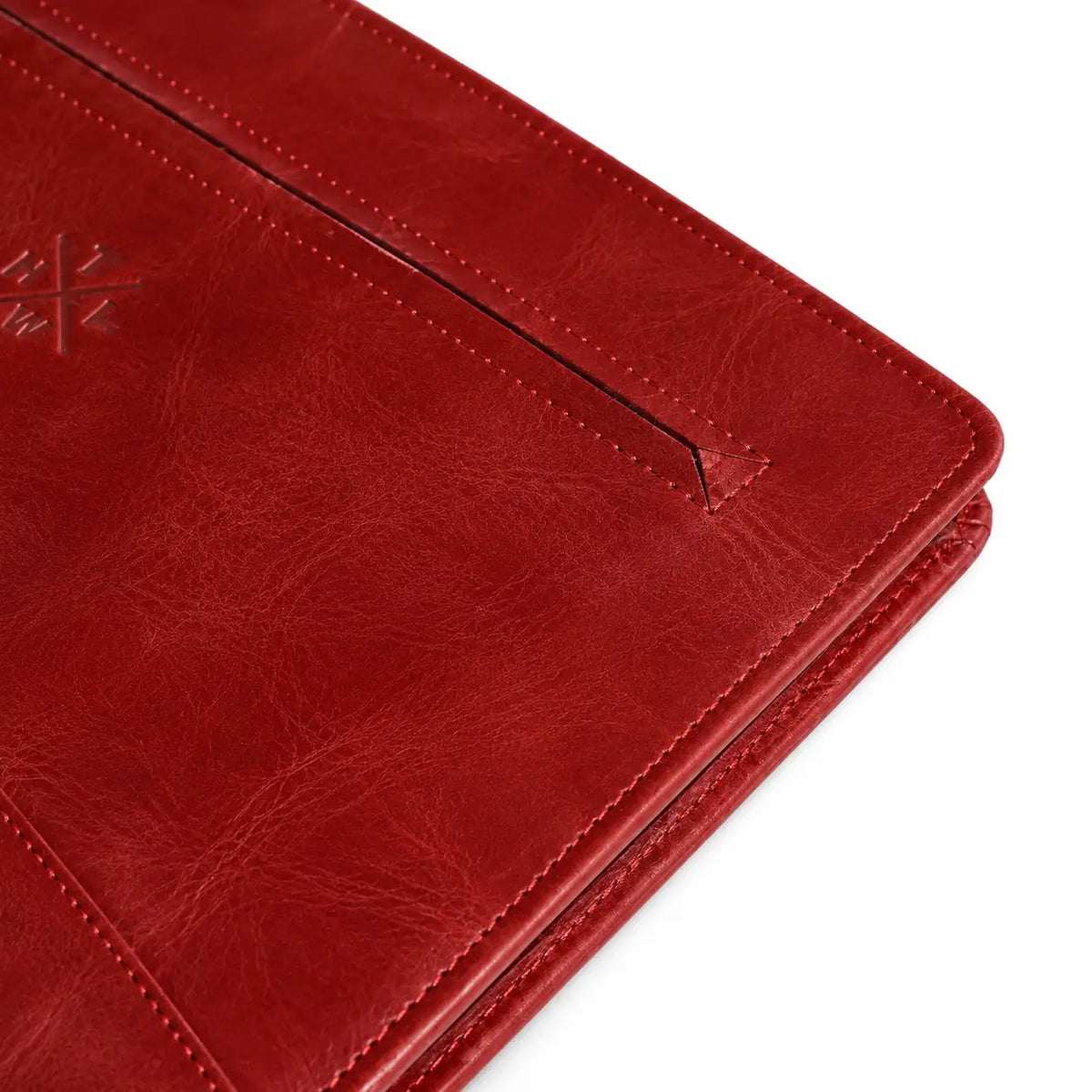 A close-up of a red textured leather planner cover or portfolio, showing a pocket, stitching, and an embossed logo on a white background.