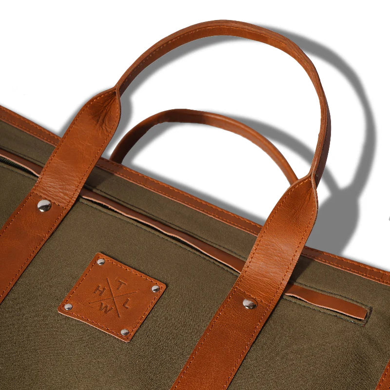 Brown leather handle and strap on a green bag with a visible brand logo.