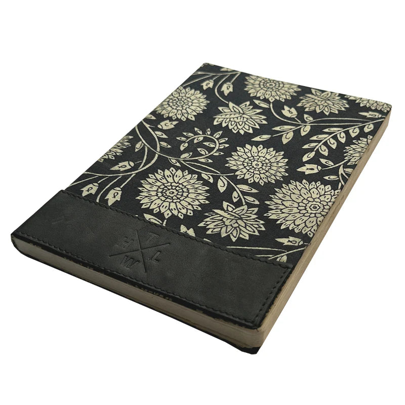 Journal with floral pattern and black leather cover on a white background