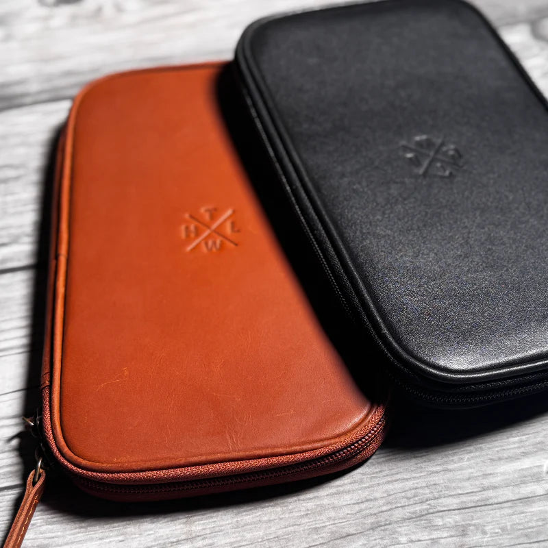 Brown and black leather cases with a logo on a wooden surface