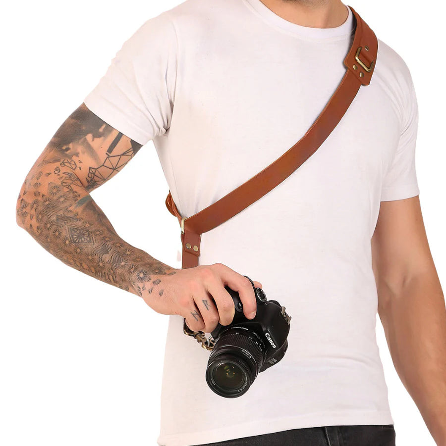 Person holding a camera with a brown leather strap on a white background
