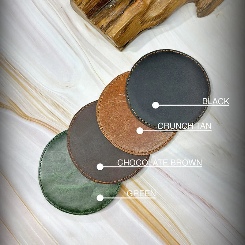 Four leather coasters in different colors on a marble surface