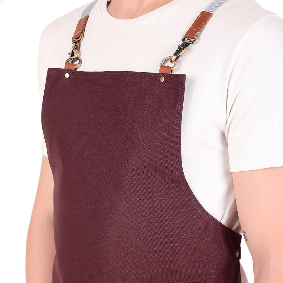Person wearing a maroon apron with leather straps on a white background