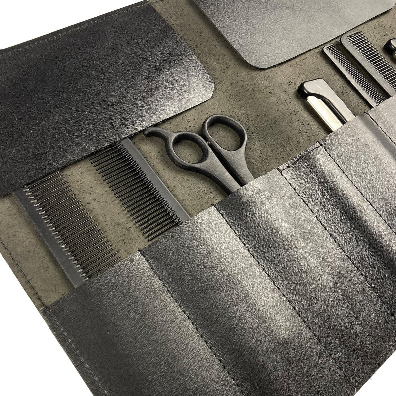 Set of grooming tools including scissors and combs in a gray case on a textured surface.