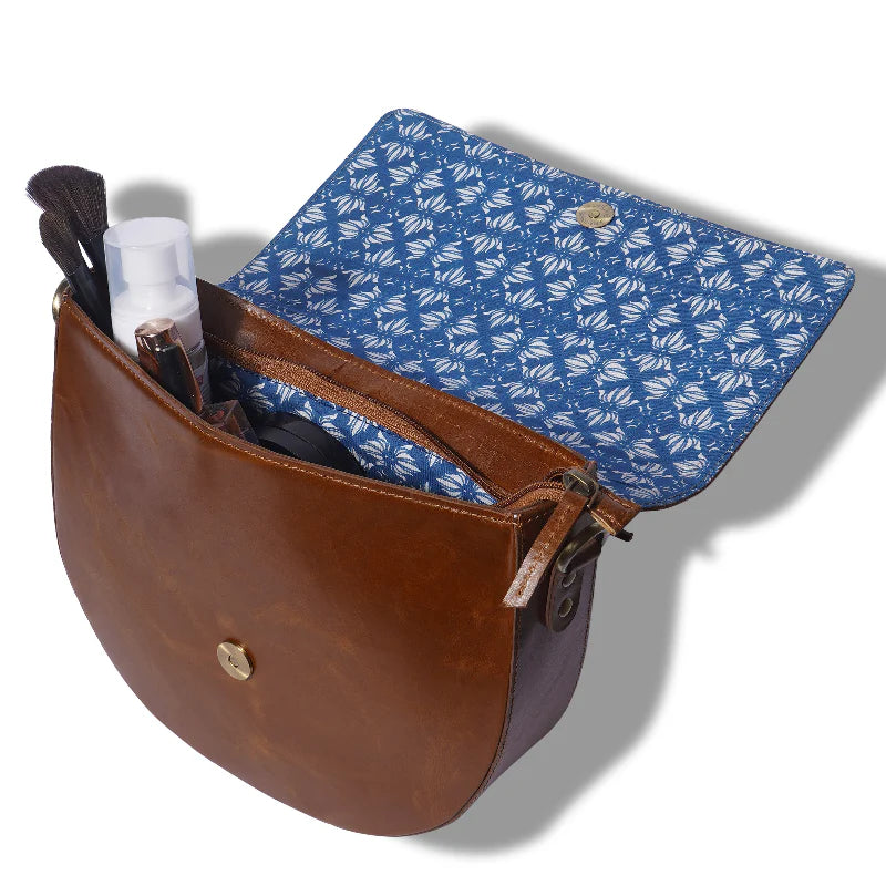 Brown leather bag with blue patterned flap on a white background