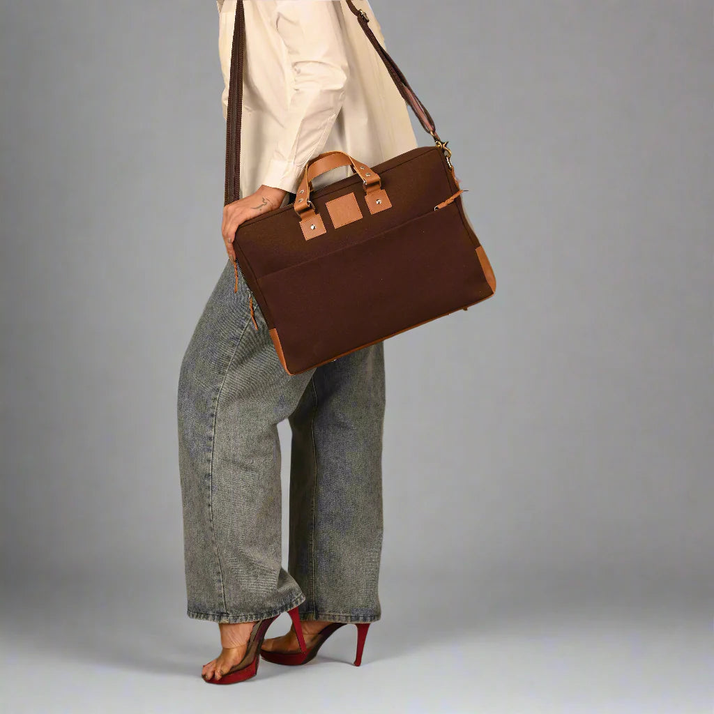 Person holding a brown leather briefcase against a gray background