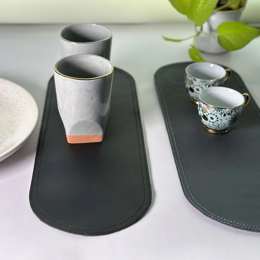 Two black trays with ceramic cups on a light surface.