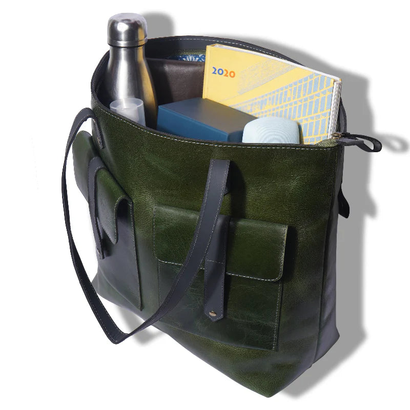 Green leather tote bag with items including a water bottle and books on a white background