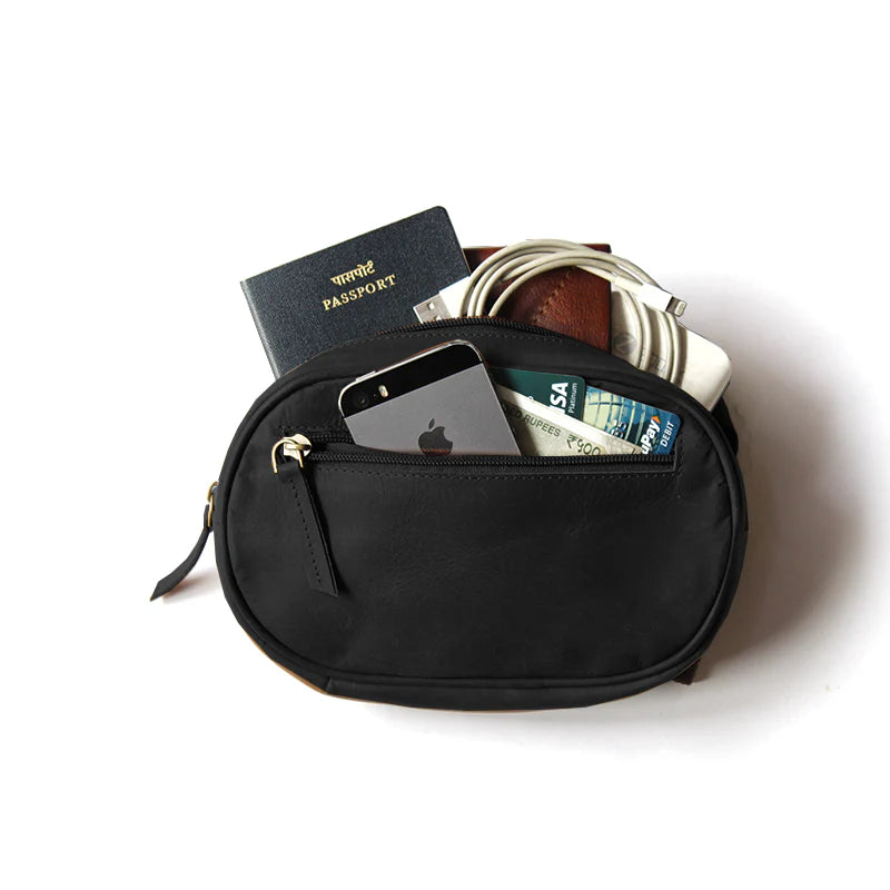Black waist bag with items including a passport, phone, and money on a white background