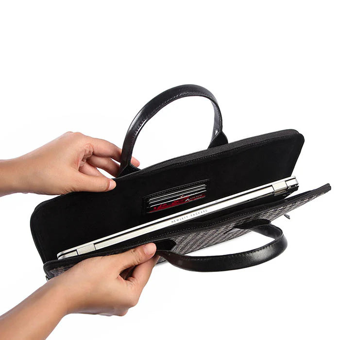 Black handbag with a silver handle held by a person on a white background