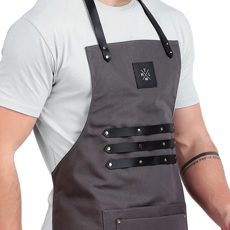 Person wearing a gray apron with black straps on a white background
