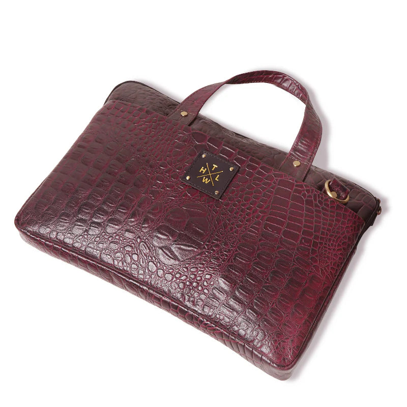 Maroon crocodile skin handbag with a brand logo on a white background
