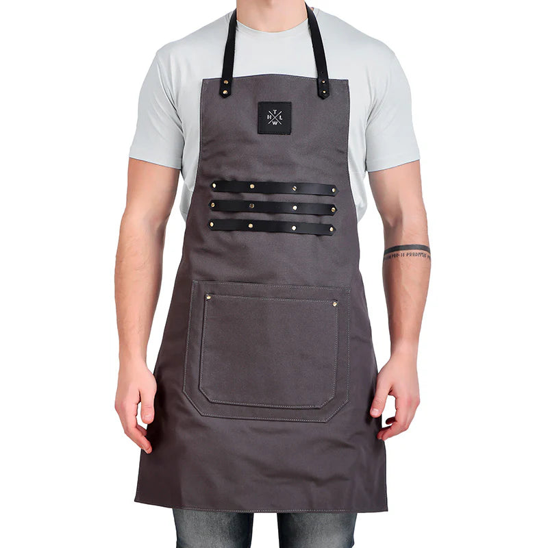 Person wearing a gray apron with black straps on a white background