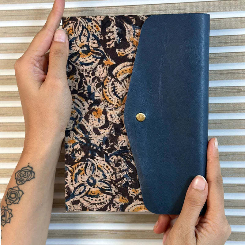 Person holding a blue wallet over a patterned fabric background