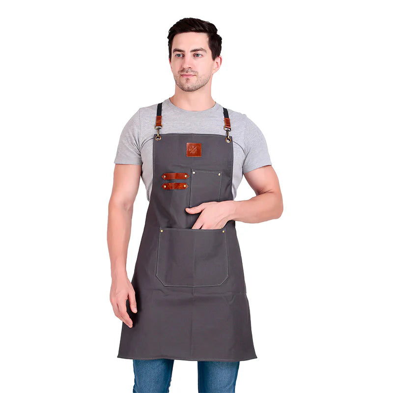 Man wearing a gray apron with leather straps on a white background