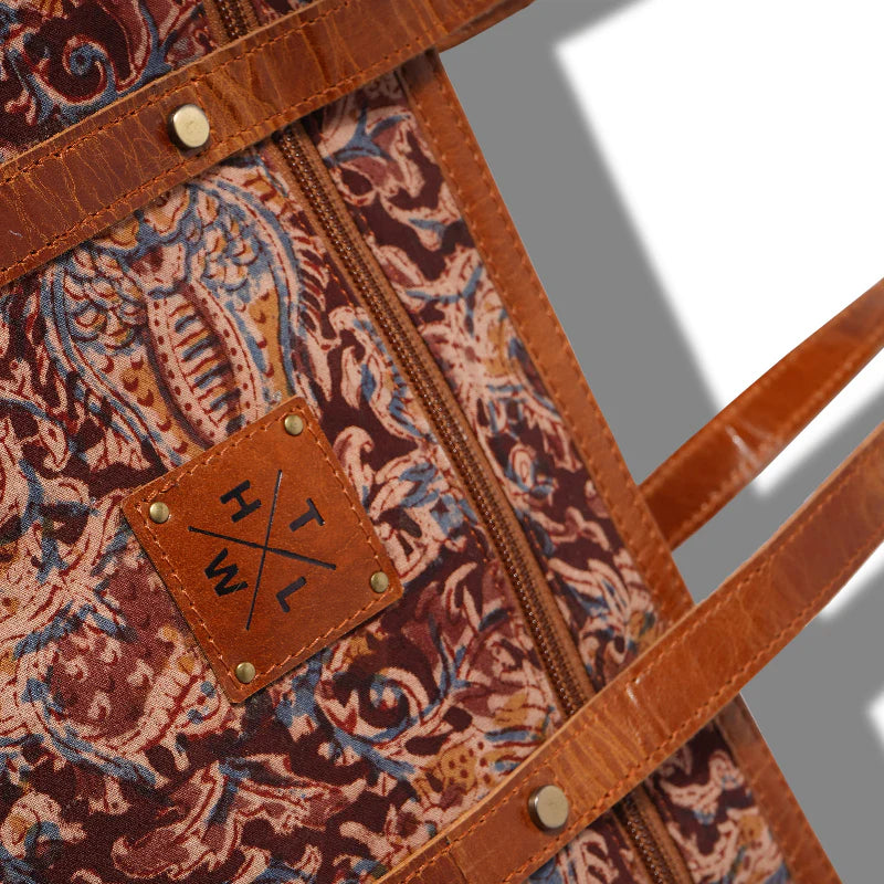 Patterned bag with leather strap and visible brand logo on a gray background