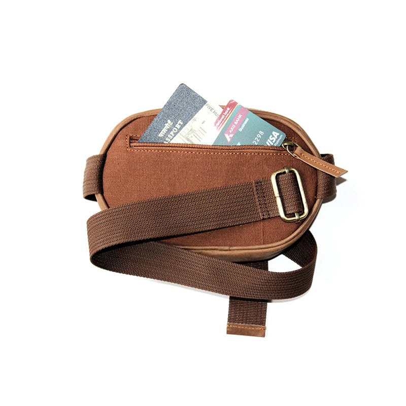 Brown crossbody bag with a strap, containing some items on a white background