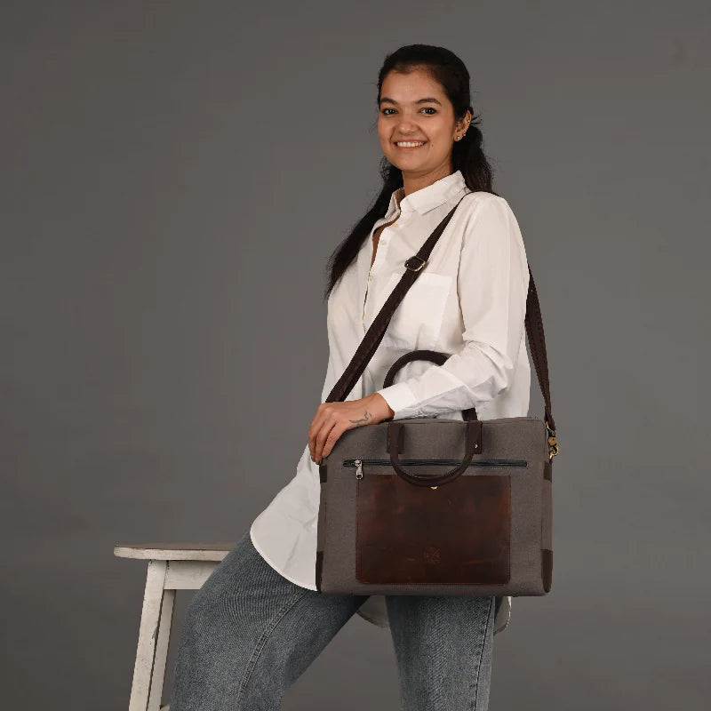 Woman holding a brown leather bag against a gray background