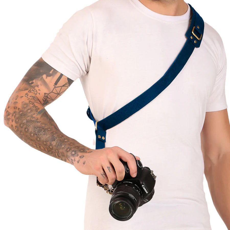 Person holding a camera with a blue strap on a white background