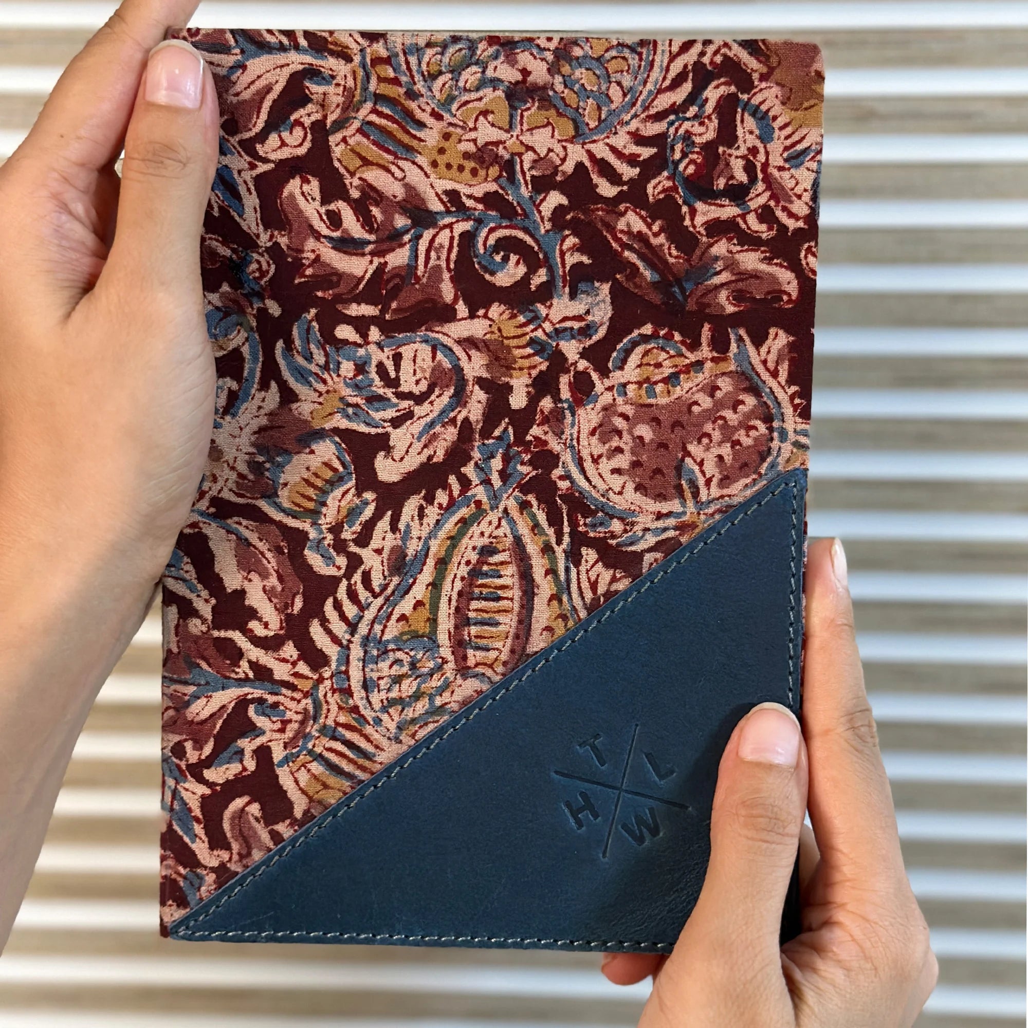 Hand holding a patterned notebook with blue corner