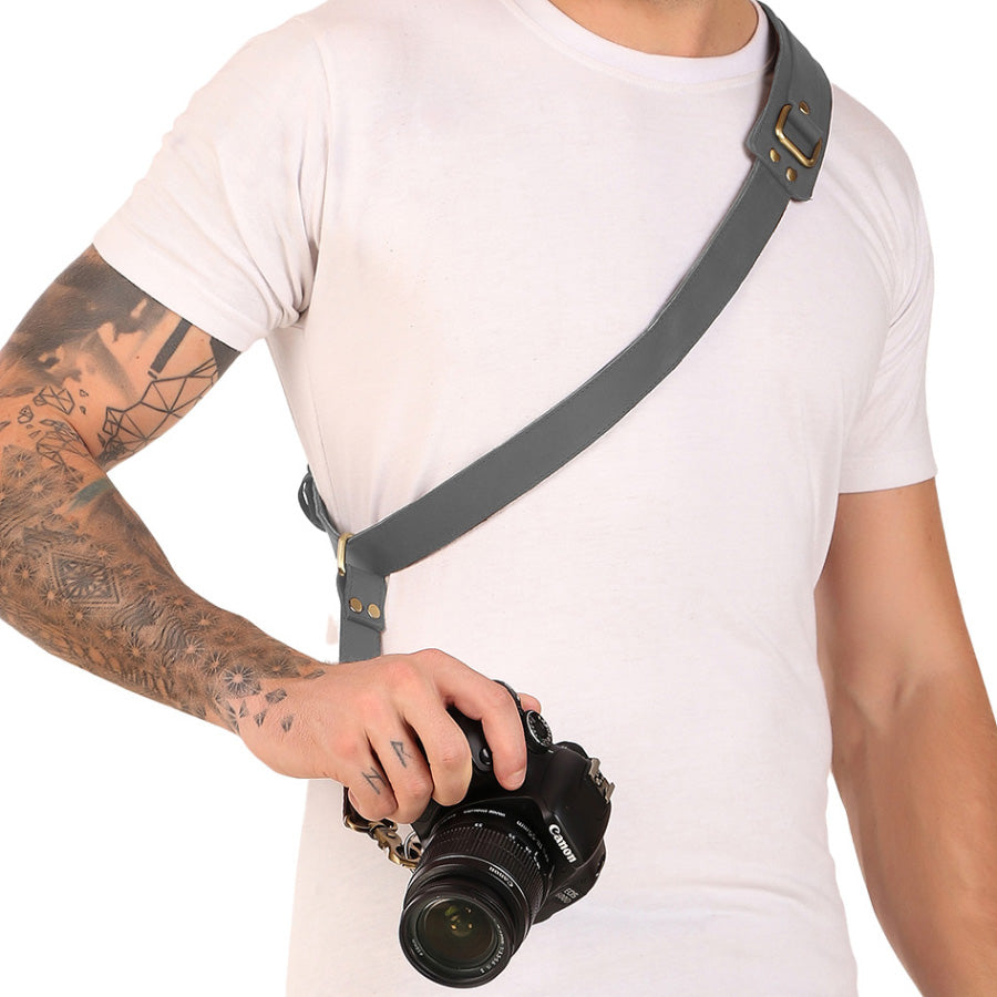 Person holding a camera with a gray strap on a white background