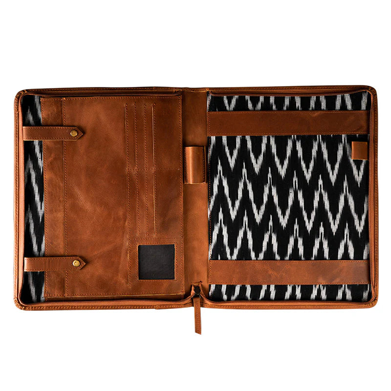 Brown leather portfolio with black and white patterned interior on a white background