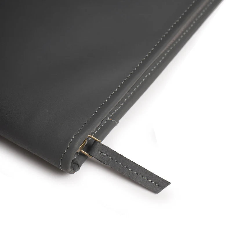 Close-up of a black leather notebook with a strap on a white background