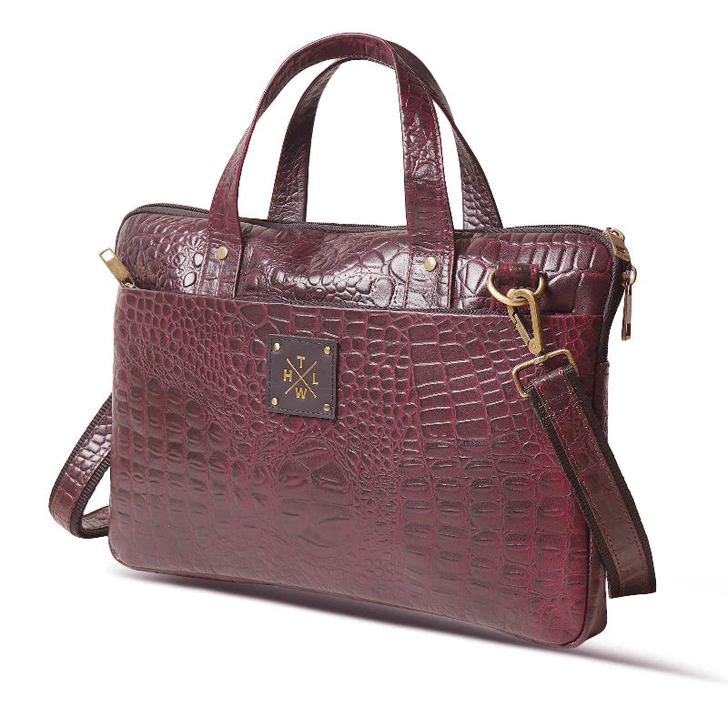 Maroon crocodile-patterned handbag with gold hardware on a white background