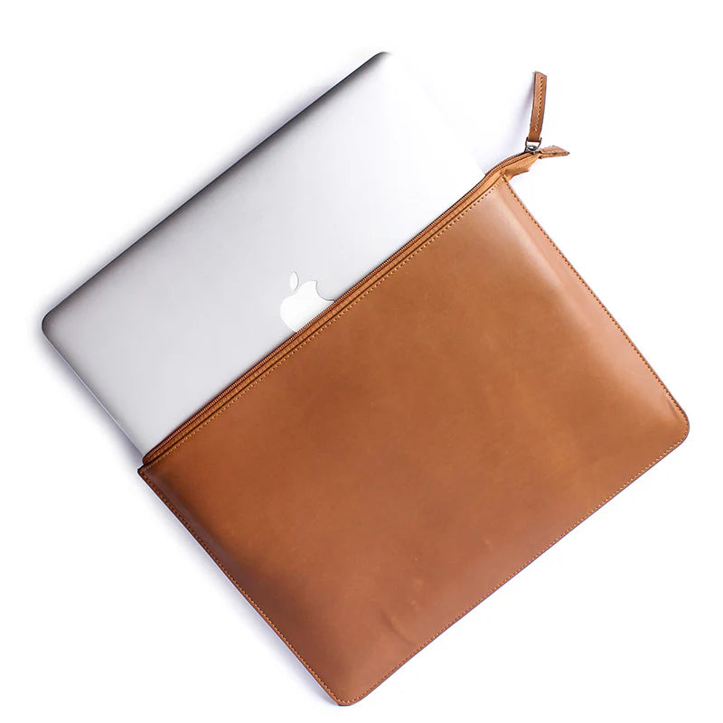 Brown leather laptop sleeve with Apple laptop inside on a white background