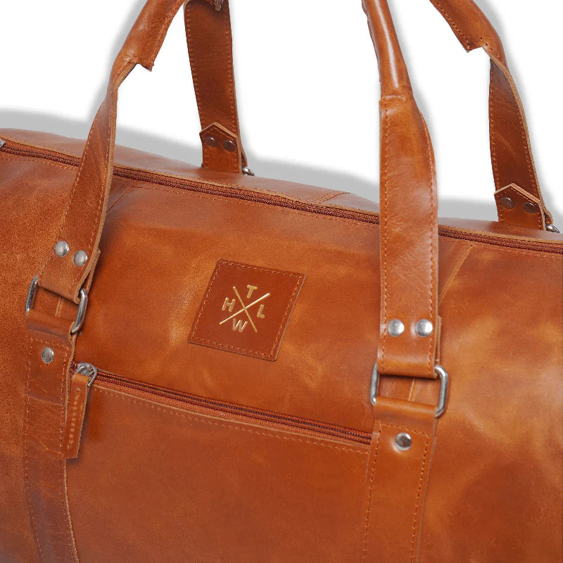Brown leather duffel bag with visible brand logo on a white background