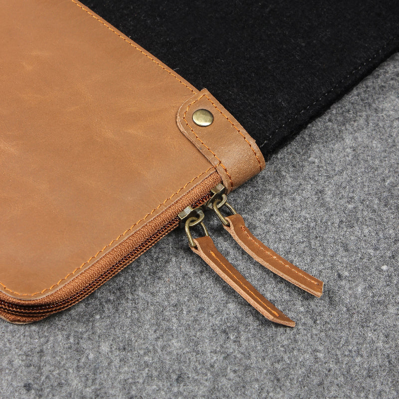 Close-up of a brown leather pouch with gold zipper on a gray surface