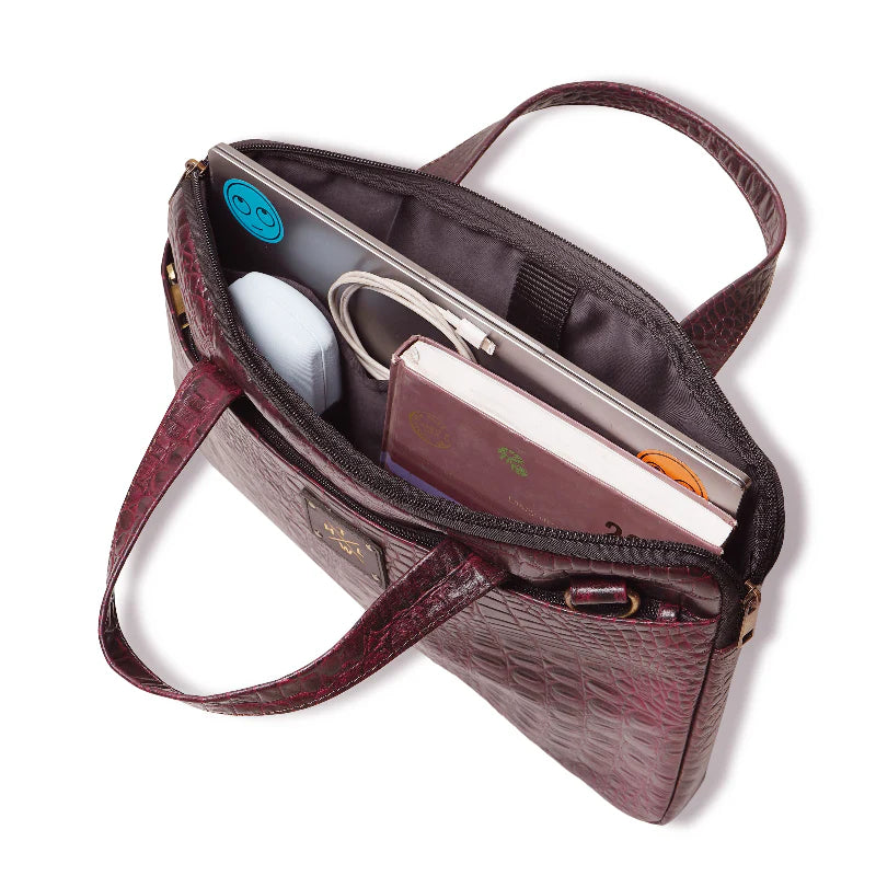 Open maroon handbag with items inside on a white background