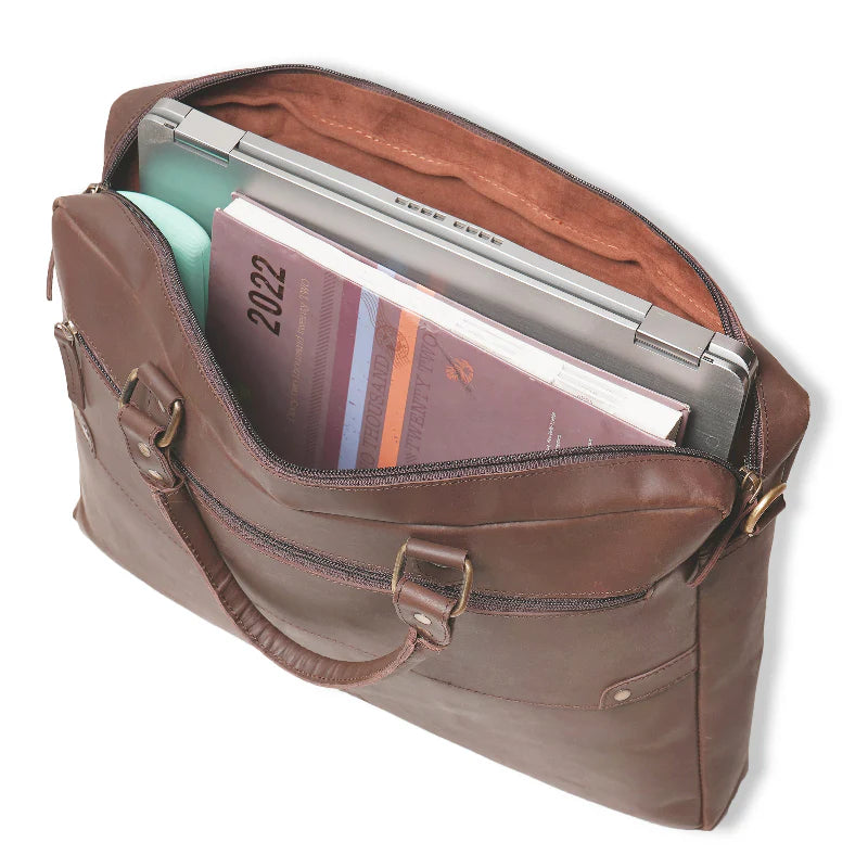 Brown leather briefcase with open lid showing a laptop and books on a white background