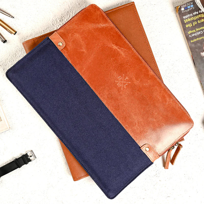 Navy and brown leather wallet on a white surface with a pen and notebook.
