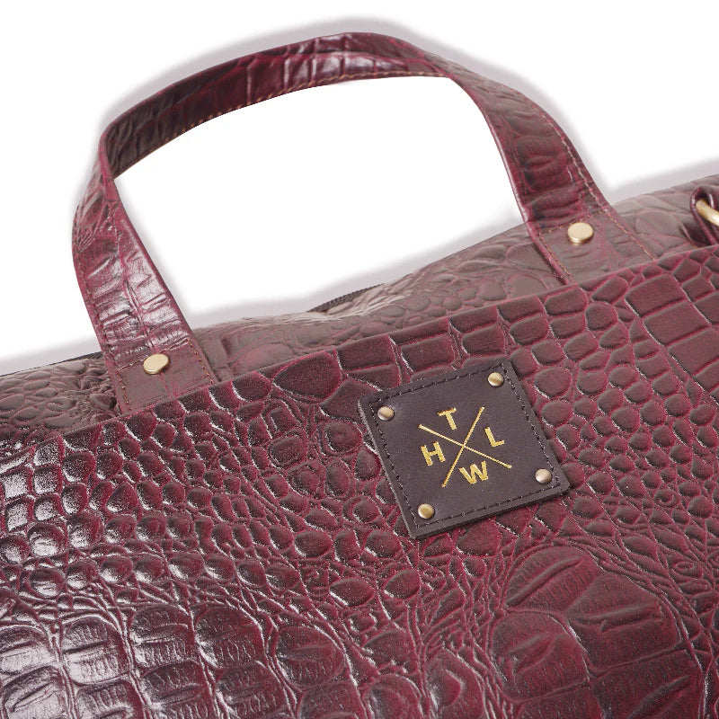 Maroon textured handbag with a visible brand logo on a white background
