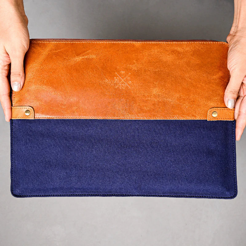 Two-toned brown and blue pouch held by hands on a gray background